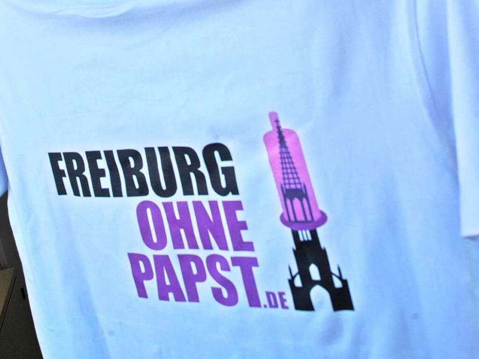 Weißes T-Shirt mit der Aufschrift "Freiburg ohne Papst" sowie dem Münster mit übergezogenem Kondom.