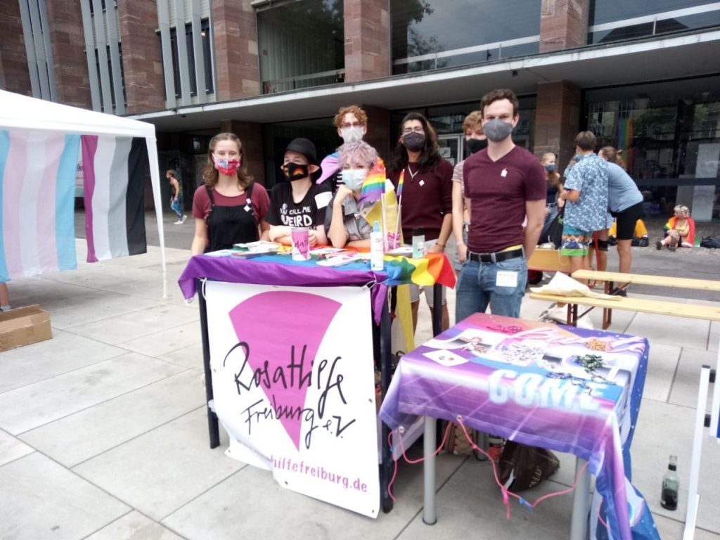 Mehrere Personen stehen mit Mundschutz am Infostand der Rosa Hilfe